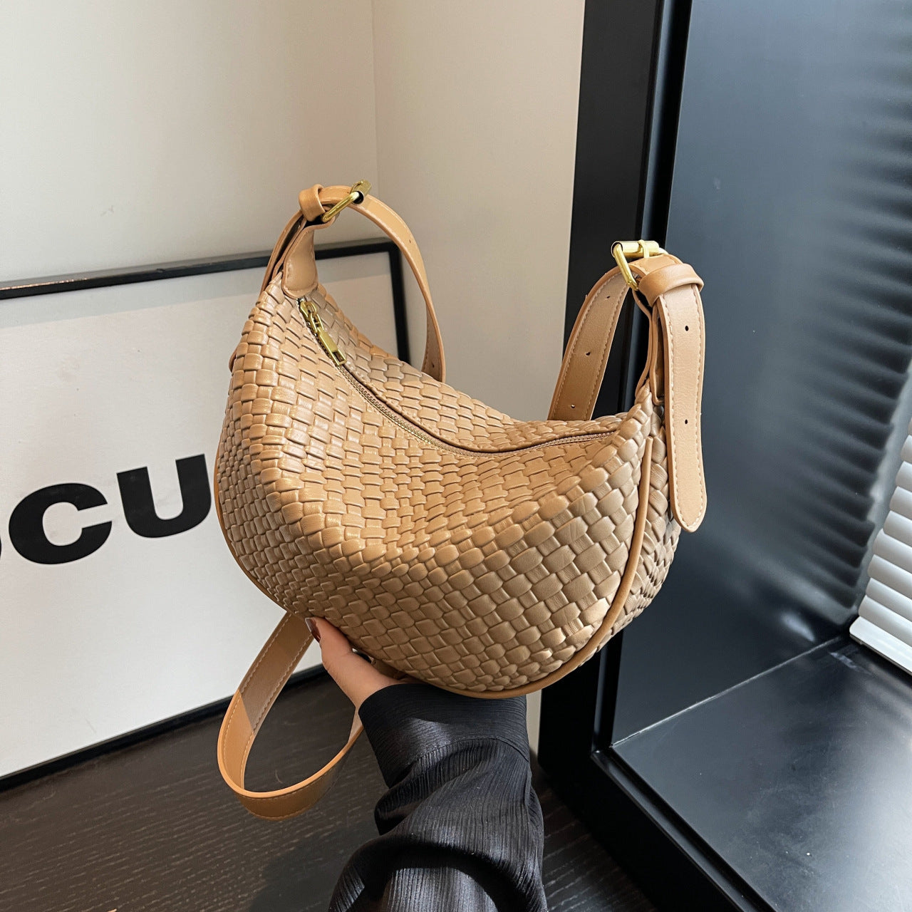 Woven handbag held by a person with a blurred background